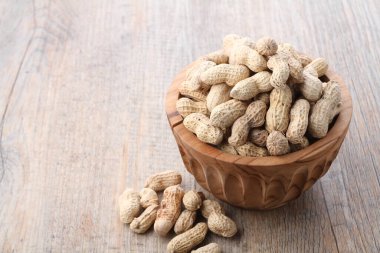 Tahta bir arka planda kasedeki fıstıklar.