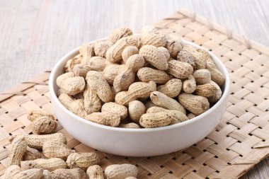 Tahta bir arka planda kasedeki fıstıklar.