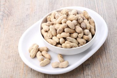 Tahta bir arka planda kasedeki fıstıklar.