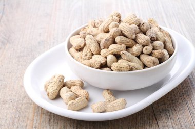 Tahta bir arka planda kasedeki fıstıklar.