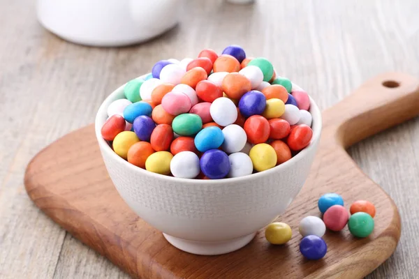 colorful candies in bowl on wooden background