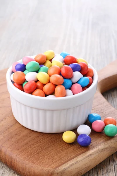 colorful candies in a bowl on a wooden background