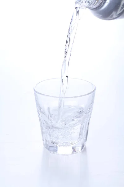 白い背景にガラスに水を注ぎ — ストック写真