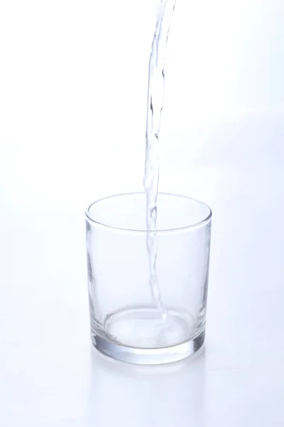 白い背景のガラスに水が流れ込み — ストック写真