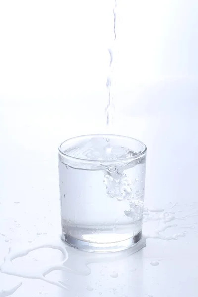Menuangkan Air Dalam Gelas Pada Latar Belakang Putih — Stok Foto