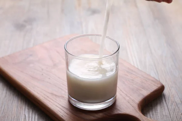 一杯牛奶和一壶新鲜果汁放在一张木制桌子上 — 图库照片