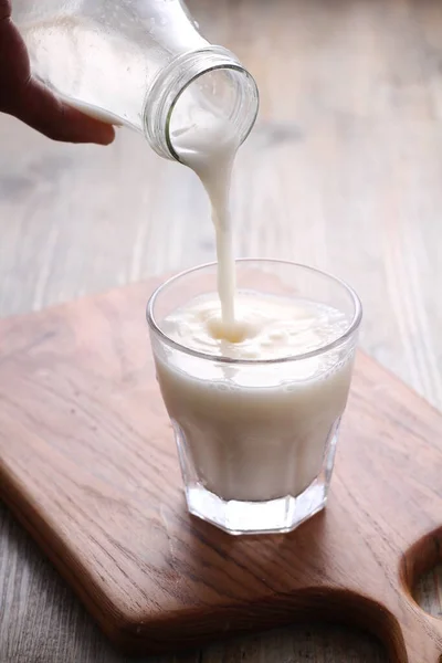 Milch Ein Glas Auf Einem Holztisch Gießen — Stockfoto