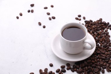 Koyu arkaplanda kahve taneleri olan bir fincan kahve. 