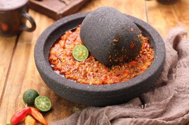 Bir kase lezzetli kırmızı biber ve baharatlar ahşap masada.