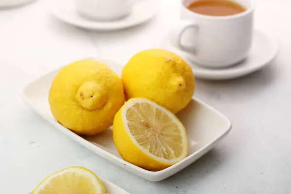 白い皿の上にお茶を入れたグラスボウルにレモンスライスが2つ — ストック写真