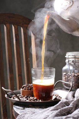 Çikolatalı kahve fincanı ve ahşap masada tarçın çubukları.