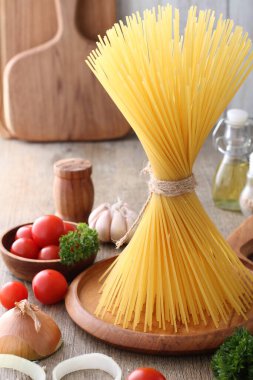 Makarna, spagetti, sarımsak, domates, fesleğen ve ahşap zemin üzerinde diğer sebzeler için malzemeler.
