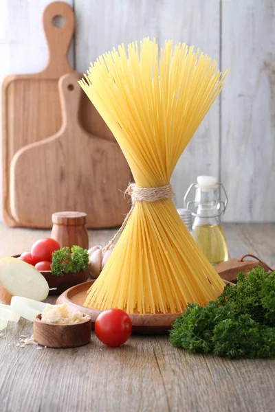 stock image pasta with tomatoes, garlic and basil on wooden background