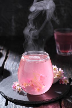 Ahşap zemin üzerinde bir bardak buzla bir fincan çay.