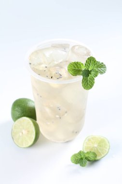 Bir bardak limonlu soğuk mojito ve beyaz arka planda nane şekeri.