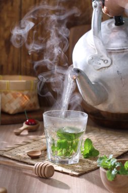 Çaydanlıkta sıcak çay ve ahşap masada bir fincan çay.