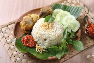 Tavuklu pilav, tavuklu pilav taze sebze ve ahşap tahtada fesleğen yaprağı ile servis edilir.