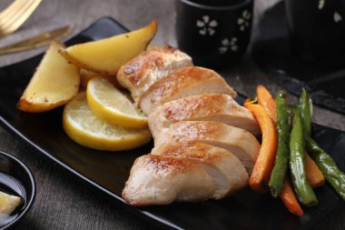 Kızarmış tavuk göğsü, patates ve sebzeli, yakın plan.