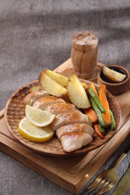 Tahta tepside patates, limon ve otla kızartılmış somon..