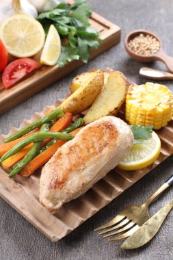 Tavuk budu, siyah tabakta ızgara sebze.