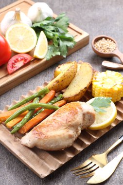 Masanın üzerinde leziz ızgara tavuk ve sebze tabağı var.