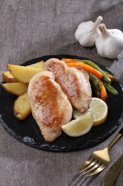 Kızarmış balık filetosu ve siyah arka planda sebze.