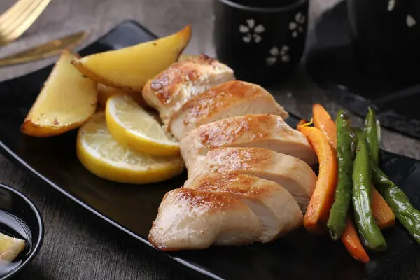 Kızarmış tavuk göğsü, patates ve sebzeli, yakın plan.