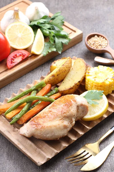 Masanın üzerinde leziz ızgara tavuk ve sebze tabağı var.