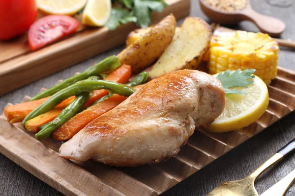 grilled chicken breast and vegetables on wooden tray