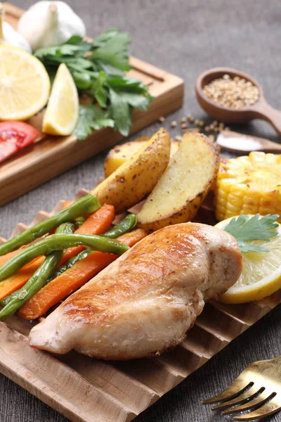 grilled chicken breast on a wooden board with vegetables
