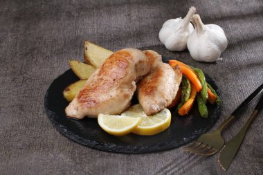 Koyu arkaplanda patates kızartmasıyla kızarmış tavuk bacağı..