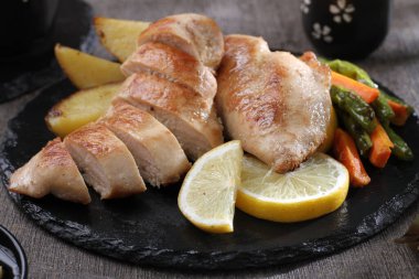 ahşap arka planda limonlu fırında tavuk göğsü ve otlar