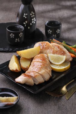 Kızarmış ördek göğsü, taze limon ve siyah tabakta siyah sos.