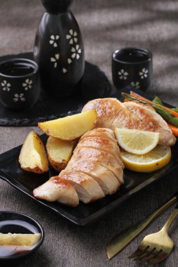 Siyah arka planda beyaz tabakta limonlu ve zencefilli kızarmış somon.