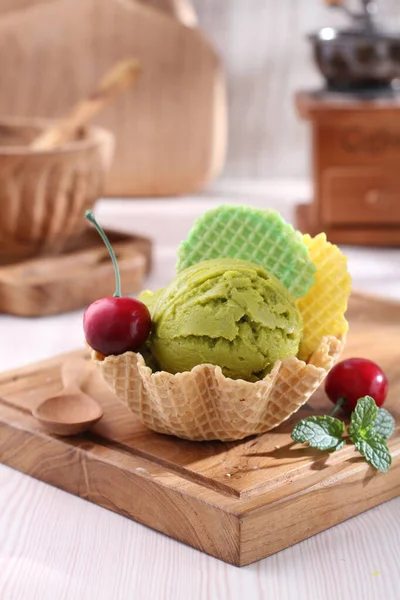 ワッフルコーンのアイスクリーム 緑の葉と木のテーブルのチョコレート — ストック写真