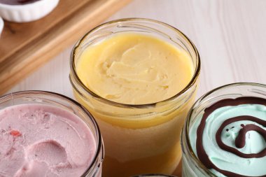 Cam bir kavanozda çeşitli kremler, renkli ve tatlı.