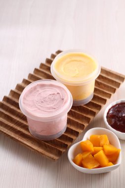 Masadaki kaselerde çeşitli yoğurt çeşitleri var.