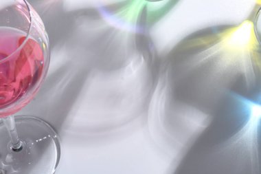 Renkli ışıklı şarap kadehi ve beyaz arka planda şarap şişesi, yakın görüş.