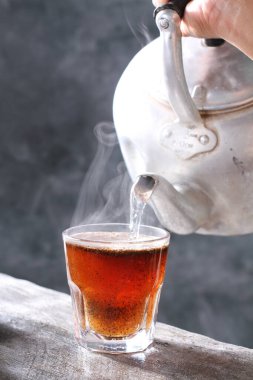 Siyah arka planda bir bardak su ve kaşıkla bir fincan çay.