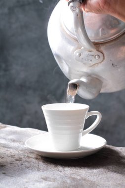 Bir fincan kahve ve gri arka planda kaşığı olan bir çaydanlık. yüksek kaliteli fotoğraf