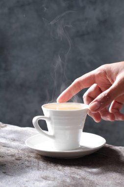 Elinde koyu bir arka planda bir fincan kahve tutan kadın.