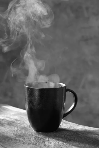 hot coffee cup with steam on the table in the morning.