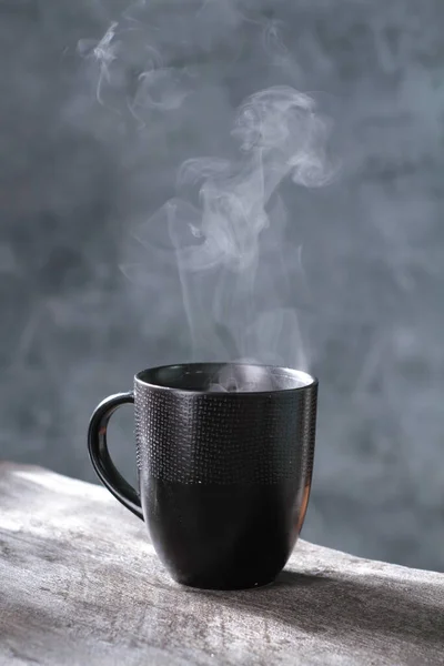 black cup with hot tea or steam in the dark.