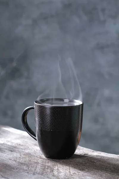 black tea cup and steam with smoke on black background