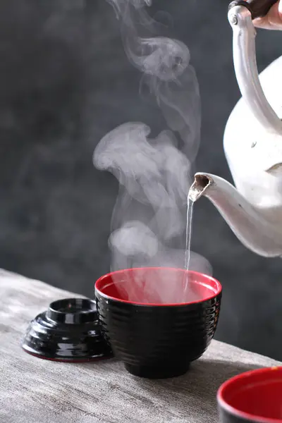 tea cup with tea kettle on black table