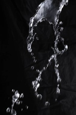 Su damlaları ve siyah boya damlaları koyu bir arkaplanda.