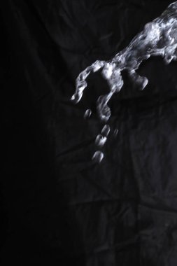 Siyah bir arka planda suya düşer, koyu bir arkaplanı vardır..