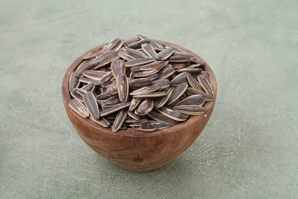 在灰背景的碗中堆放大量的干黑芝麻种子 — 图库照片
