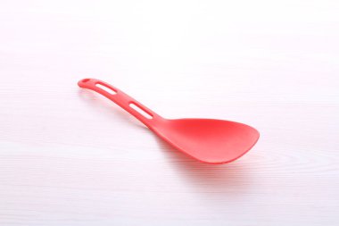 Beyaz arkaplanda kırmızı plastik kaşık.