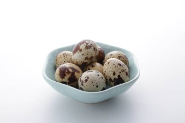 Beyaz arka planda bir tabakta bıldırcın yumurtası.